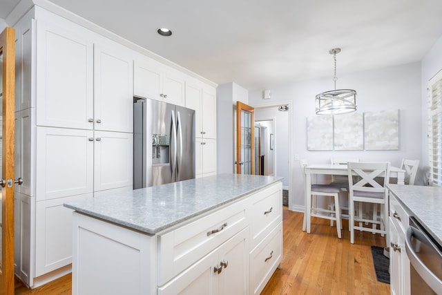 kitchen featuring light stone countertops, decorative light fixtures, appliances with stainless steel finishes, light wood-style floors, and white cabinetry