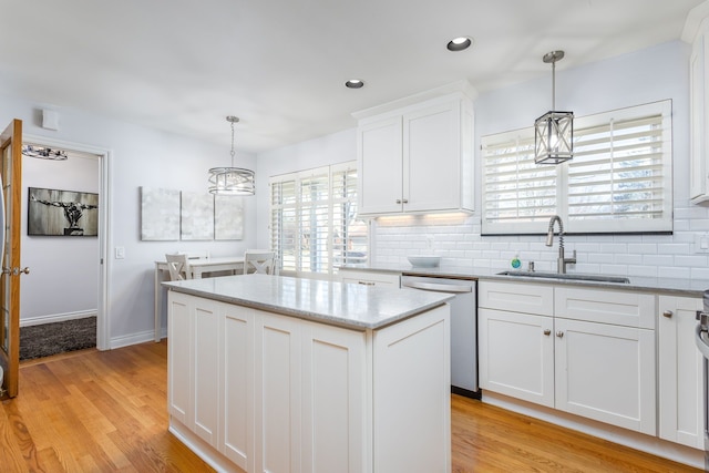 kitchen with light wood-style flooring, a sink, stainless steel dishwasher, white cabinets, and decorative backsplash