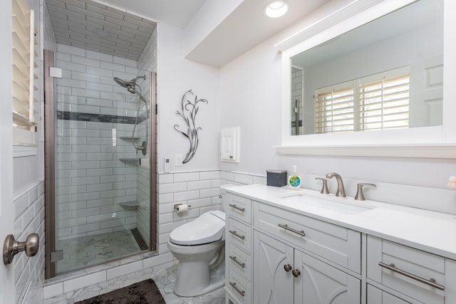 full bathroom featuring vanity, a wainscoted wall, a stall shower, tile walls, and toilet