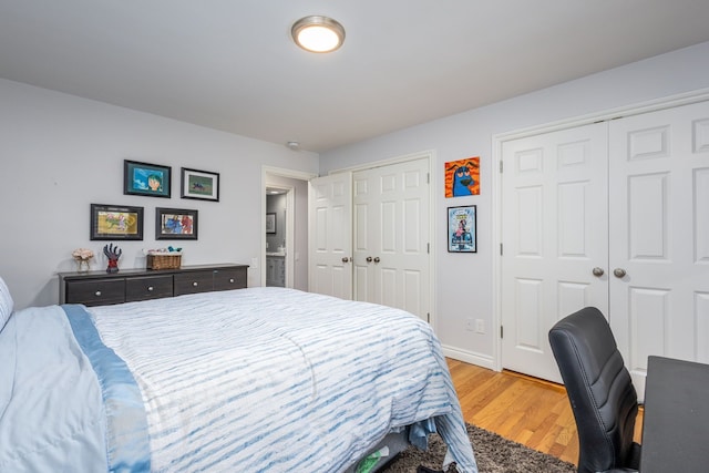 bedroom with light wood-style flooring, two closets, and baseboards