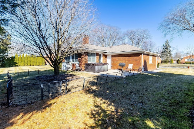 back of house with a patio, fence, brick siding, a chimney, and a hot tub