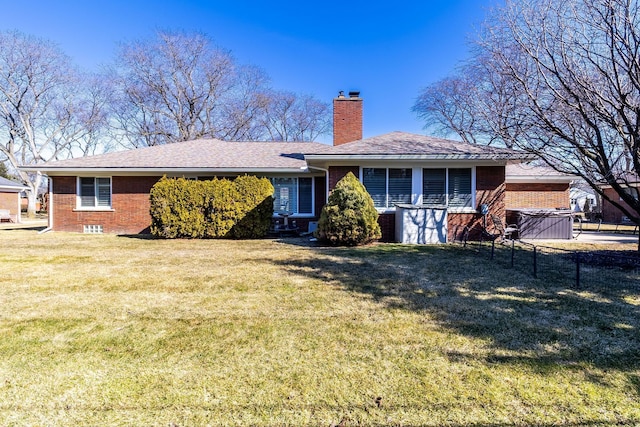 back of property with brick siding, a chimney, a yard, and fence