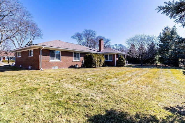 rear view of property with brick siding, a lawn, and a chimney