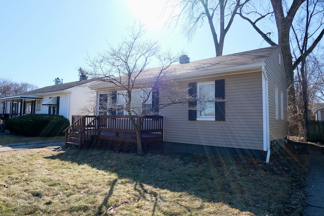 view of front of property featuring a chimney, a wooden deck, and a front yard