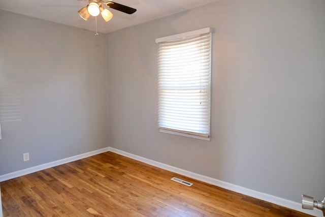 spare room with visible vents, a ceiling fan, baseboards, and wood finished floors