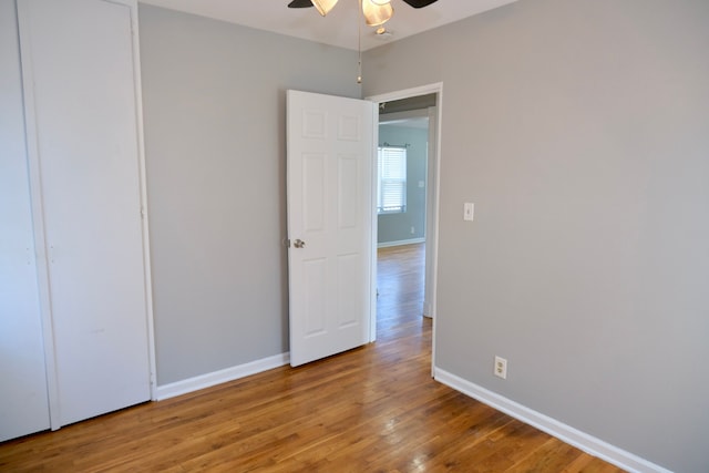 unfurnished room with baseboards, wood finished floors, and a ceiling fan