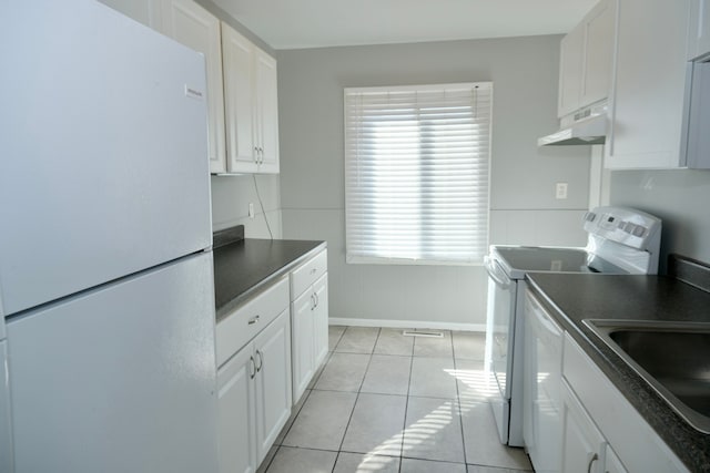 kitchen featuring under cabinet range hood, white appliances, dark countertops, and white cabinets