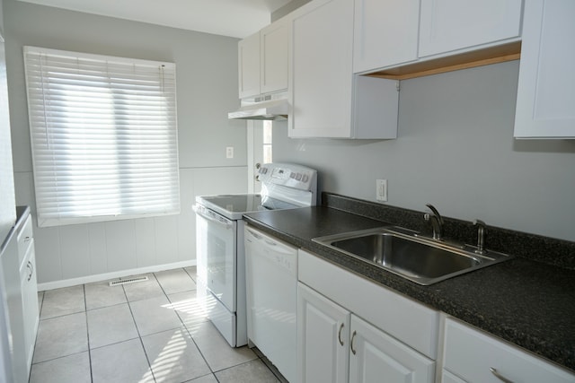 kitchen with white appliances, dark countertops, under cabinet range hood, and a sink