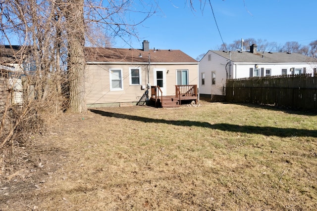 rear view of house with a chimney, fence, a lawn, and a wooden deck