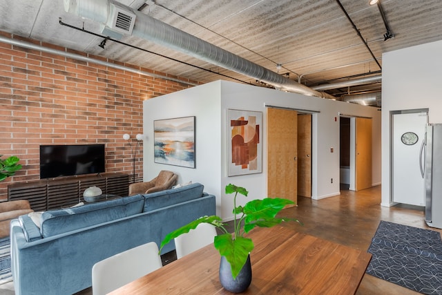 living area with track lighting, visible vents, brick wall, and finished concrete floors