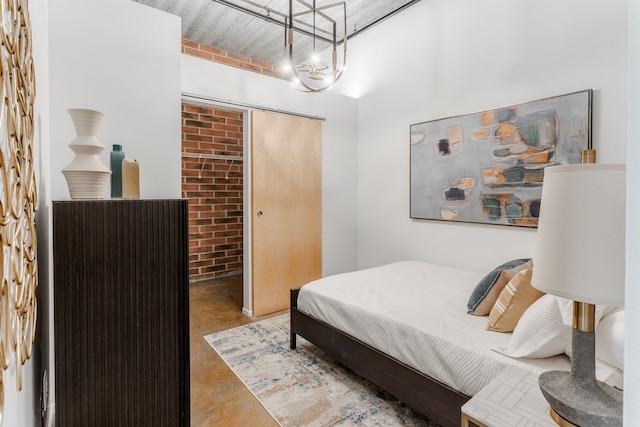 bedroom featuring a closet, brick wall, and concrete flooring