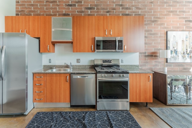 kitchen with glass insert cabinets, brown cabinetry, stone countertops, stainless steel appliances, and a sink