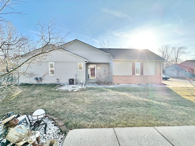 view of front of home with brick siding, central AC, and a front lawn