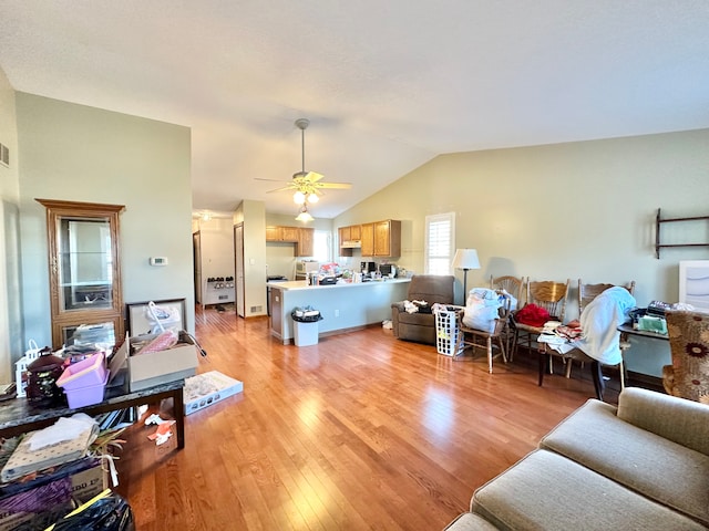 living area with vaulted ceiling, a ceiling fan, light wood-type flooring, and visible vents