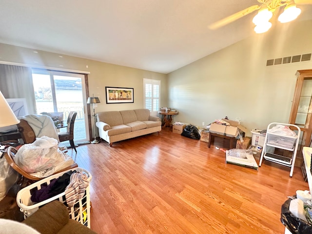 living room featuring vaulted ceiling, wood finished floors, and visible vents