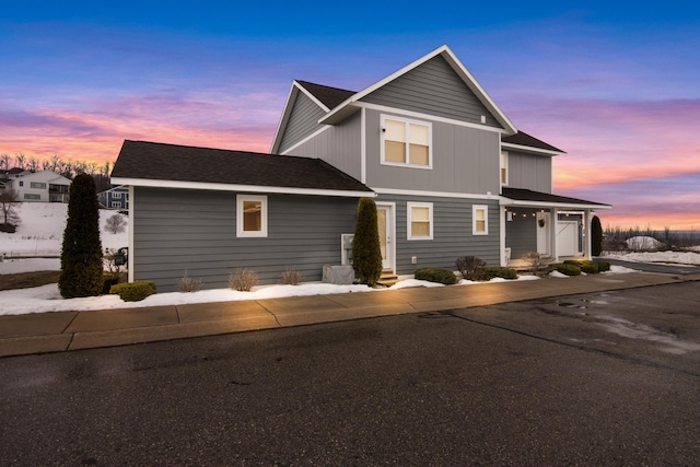 traditional-style home with a garage and roof with shingles