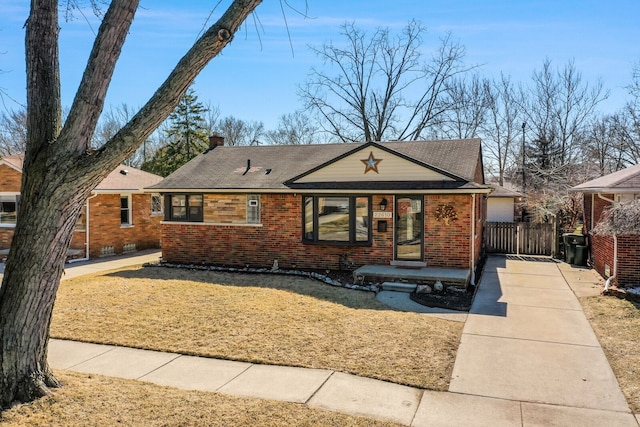 ranch-style house featuring a front lawn, fence, concrete driveway, brick siding, and a chimney