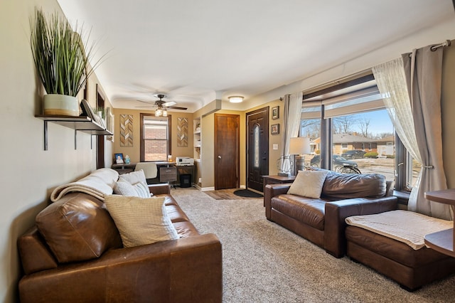 carpeted living area with baseboards and a ceiling fan