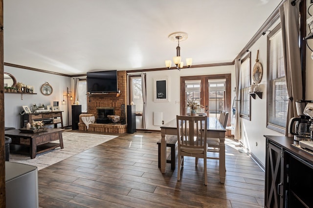 dining space featuring a notable chandelier, a brick fireplace, dark wood-style floors, and crown molding