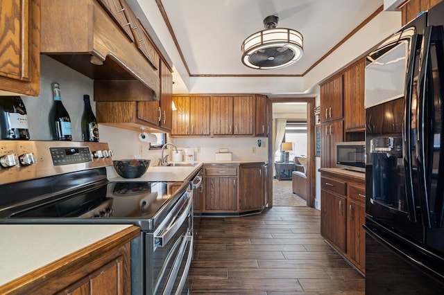 kitchen with brown cabinets, a tray ceiling, dark wood-style floors, appliances with stainless steel finishes, and light countertops