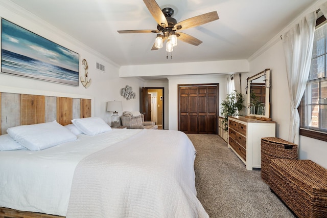 carpeted bedroom with crown molding, visible vents, a closet, and ceiling fan