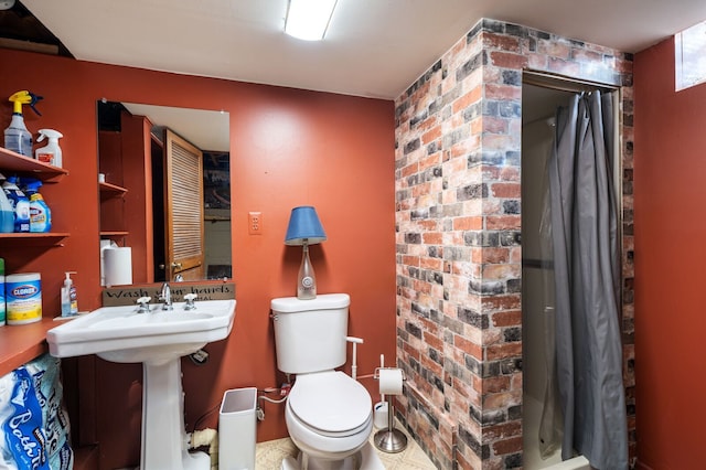 bathroom featuring a shower with shower curtain, toilet, and brick wall