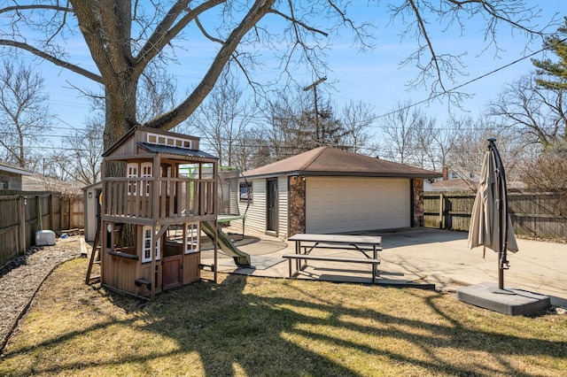 view of play area with an outbuilding, a fenced backyard, a lawn, and a patio