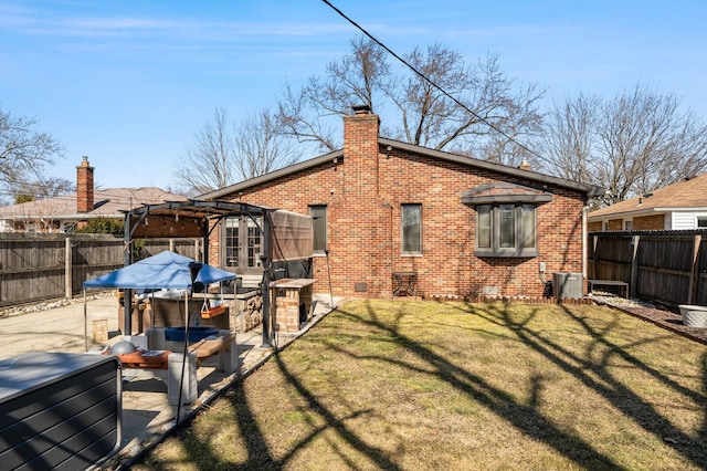 back of property with brick siding, a chimney, a yard, a fenced backyard, and a patio