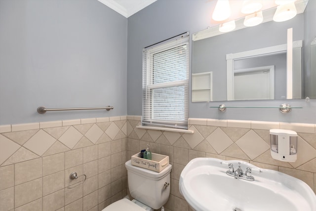 half bath with tile walls, toilet, wainscoting, and a sink