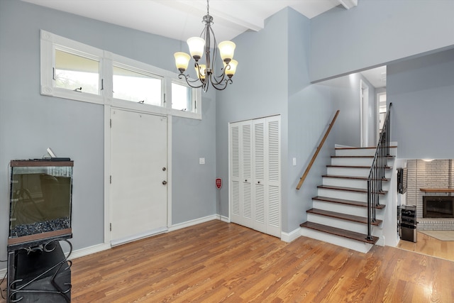 foyer entrance with beam ceiling, wood finished floors, a high ceiling, baseboards, and stairs