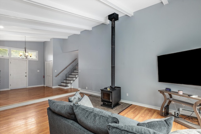 living area with stairs, a baseboard radiator, wood finished floors, and a wood stove