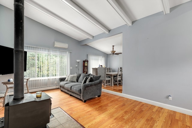 living area with baseboards, an AC wall unit, lofted ceiling with beams, a wood stove, and wood finished floors