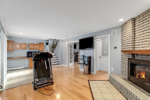 workout room with visible vents, a baseboard radiator, light wood-style flooring, recessed lighting, and a brick fireplace