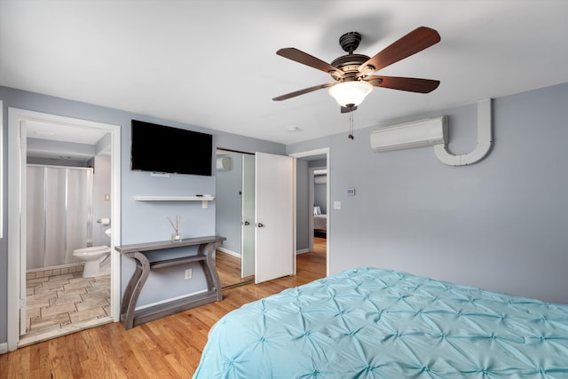 bedroom with connected bathroom, baseboards, an AC wall unit, wood finished floors, and a ceiling fan