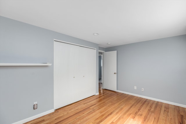 unfurnished bedroom featuring a closet, baseboards, and wood finished floors