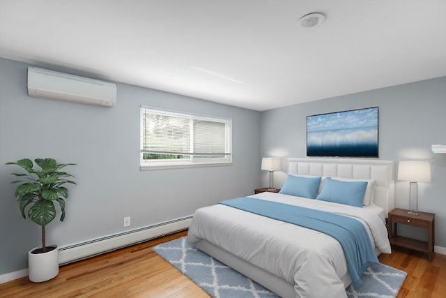 bedroom featuring a wall mounted AC, wood finished floors, baseboards, and a baseboard radiator