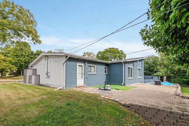 rear view of house with a yard, a patio, brick siding, and fence