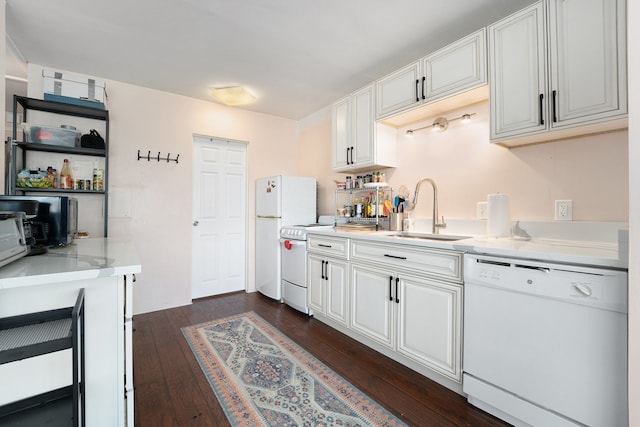 kitchen with a sink, white appliances, dark wood-style floors, and white cabinetry