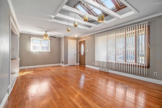 interior space with hardwood / wood-style floors, crown molding, a skylight, and baseboards