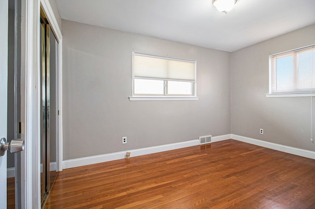 empty room with visible vents, baseboards, and wood finished floors