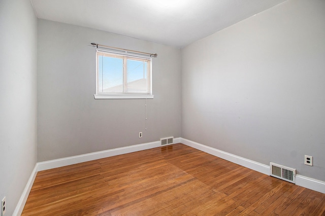 unfurnished room featuring light wood-type flooring, visible vents, and baseboards