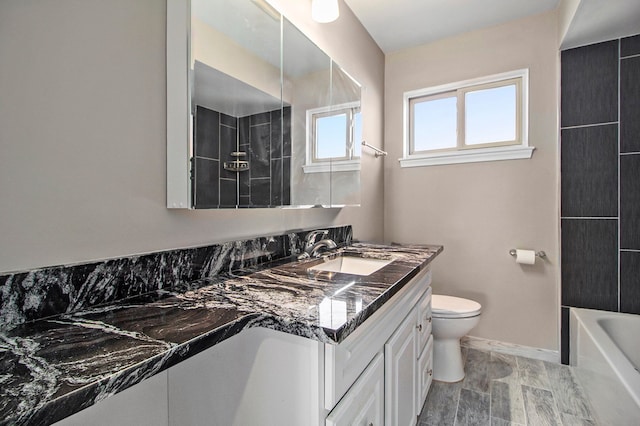 full bath featuring toilet, vanity, and baseboards