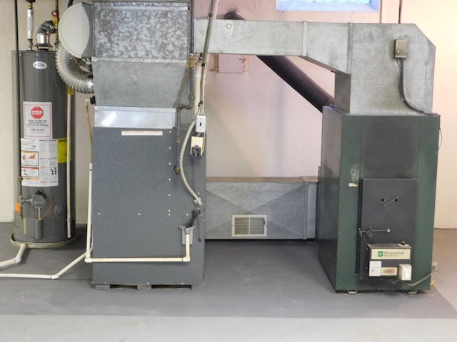 utility room with heating unit, visible vents, and gas water heater