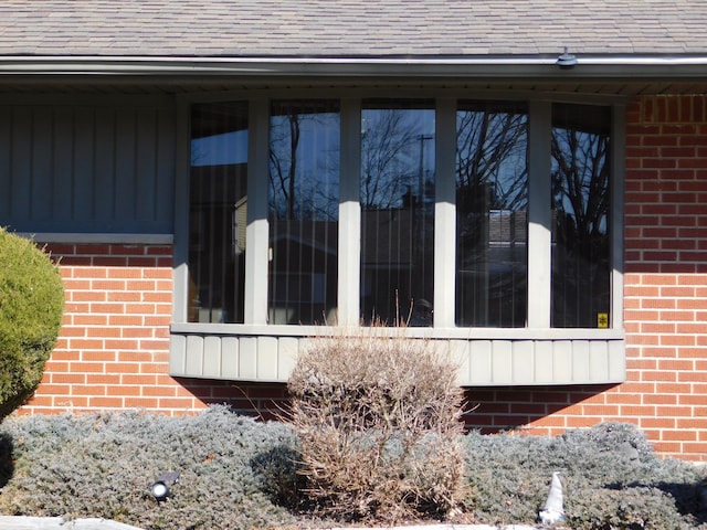 view of property exterior with brick siding and a shingled roof