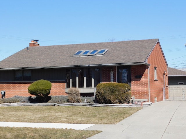 single story home featuring a front lawn, a chimney, brick siding, and a shingled roof