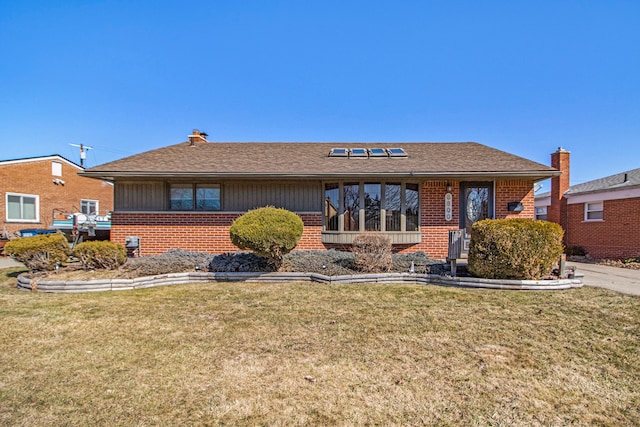 view of front of house featuring brick siding, a front yard, and a shingled roof