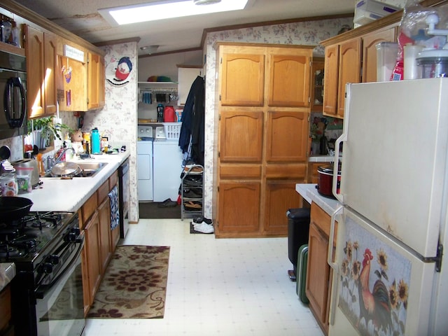 kitchen with light floors, washing machine and clothes dryer, a sink, black appliances, and light countertops