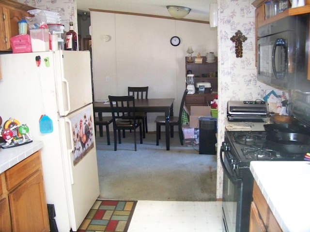 kitchen with tile countertops, light floors, black appliances, and wallpapered walls