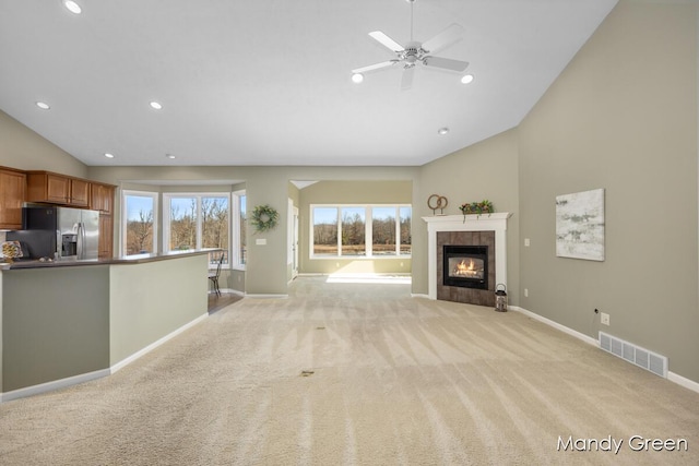 unfurnished living room featuring visible vents, plenty of natural light, light colored carpet, and a tile fireplace