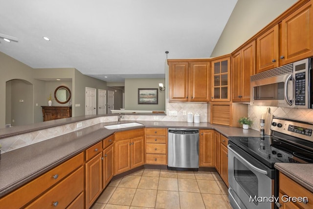 kitchen with a sink, decorative backsplash, dark countertops, and appliances with stainless steel finishes